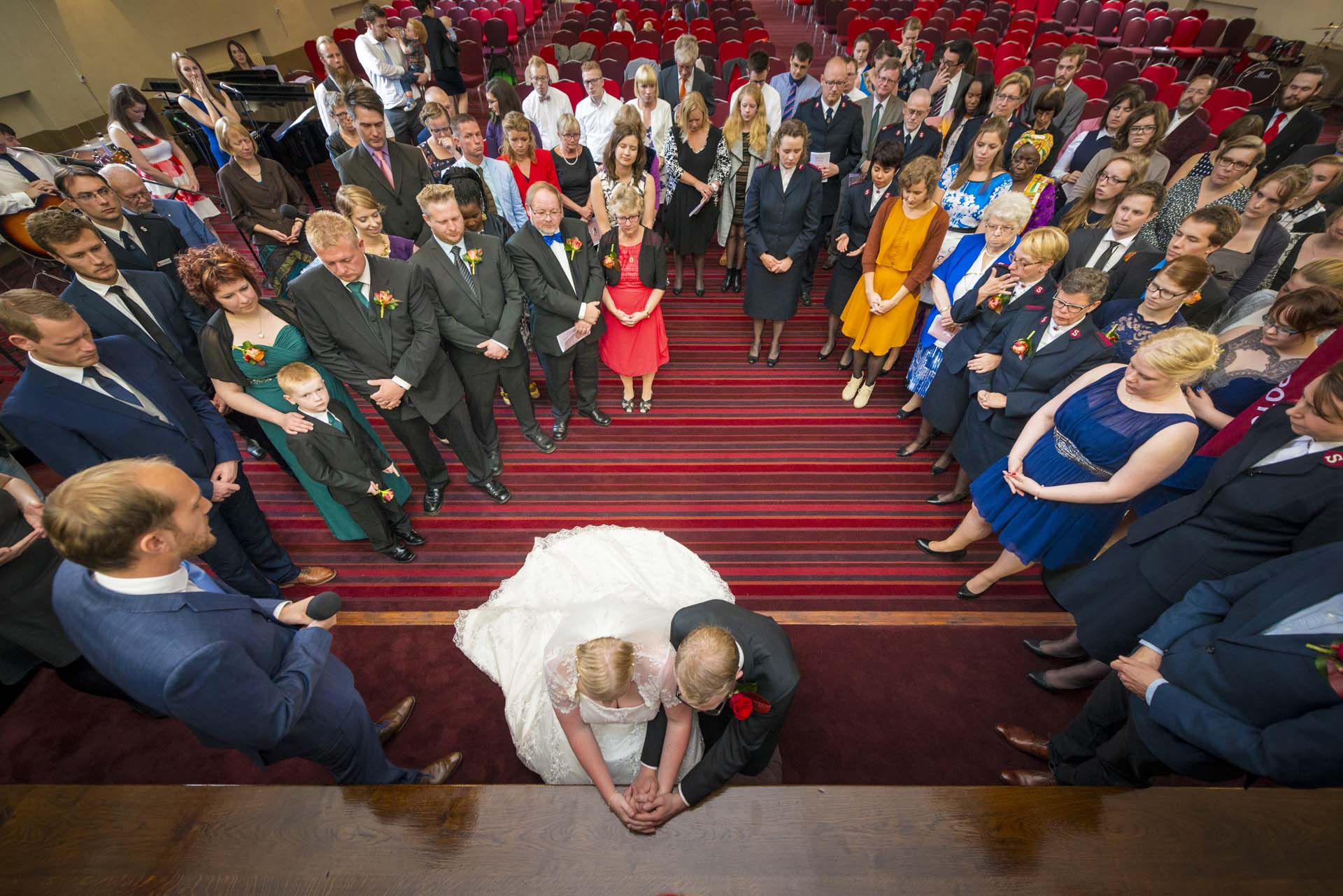 Kneeling to pray with the family gathered around Camberwell south london wedding photographer article on extreme wide angle lenses
