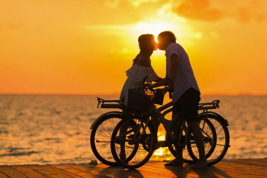 Bride and groom bixcycles by the sea pexels-asad-photo-maldives-1024970